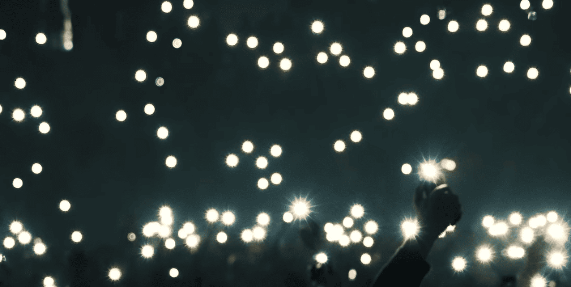 Público en un evento cultural iluminando con móviles durante un espectáculo en vivo